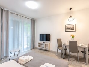 A modern hotel room with a bed, a TV, a dining table with chairs, and a small balcony. - Strandnahe, gemütliche Ferienwohnung in Swinemünde by Interhome (Swinoujscie)