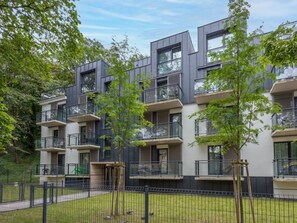 A modern multi-story residential building with balconies, surrounded by greenery and a fenced yard. - Strandnahe, gemütliche Ferienwohnung in Swinemünde by Interhome (Swinoujscie)