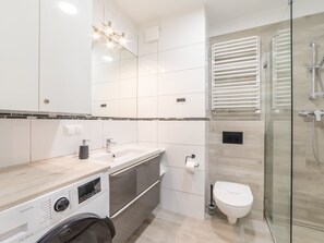 A modern bathroom with a glass shower enclosure, a built-in washing machine, and a toilet. - Strandnahe, gemütliche Ferienwohnung in Swinemünde by Interhome (Swinoujscie)