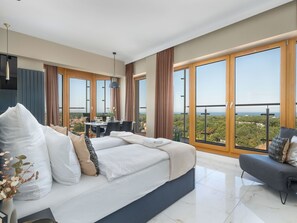 Ein modernes Schlafzimmer mit großem Bett, Essbereich und Balkon mit schöner Aussicht.