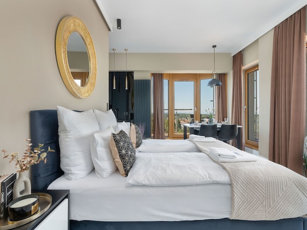 Ein modernes Hotelzimmer mit einem großen Bett, einer Essecke und Blick auf die Stadt.