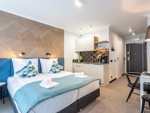 Ein modernes Hotelzimmer mit einem großen Bett, einer Küchenzeile, einem Schreibtisch und einem Badezimmer.