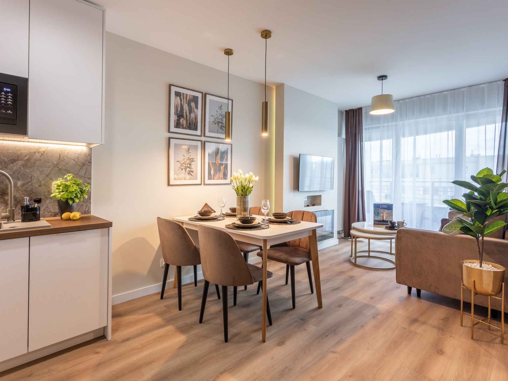 Une cuisine moderne dotée d’un four encastré, un coin repas avec une table et des chaises, et un espace de vie avec un canapé et une table basse.
