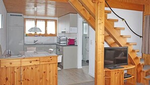 Een kleine keuken met houten kastjes, een inbouwfornuis en een raam boven de spoelbak.