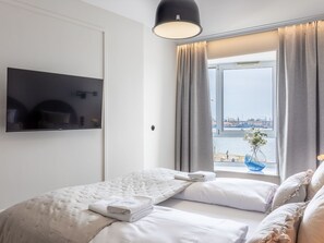 Ein modernes Hotelzimmer mit einem Bett, einem Flachbildfernseher und einem Vorhangfenster.