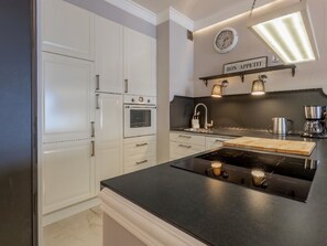 A kitchen with white cabinetry, a black countertop, a built-in oven, a sink, and a coffee maker. - Strandnahe Ferienwohnung Celeste by Interhome (Swinoujscie)