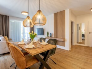 A modern dining area with a wooden table set for four, surrounded by comfortable seating. - Ferienappartement Matejki direkt an der Promenade by Interhome (Swinoujscie)