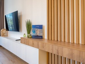 A modern living room with a flat-screen TV, a wooden console table, and a windmill-themed poster. - Ferienappartement Matejki direkt an der Promenade by Interhome (Swinoujscie)
