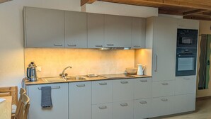 A modern kitchen with grey cabinets, a stainless steel sink, and a built-in oven. - Margrit West by Interhome (Lauterbrunnen)