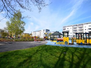A playground with various play structures, surrounded by grass and trees, with residential buildings in the background. - Apartment Verde in Swinemünde by Interhome (Swinoujscie)