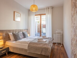 A bedroom with a bed, bedside table, lamp, and a view of the outside balcony. - Apartment Verde in Swinemünde by Interhome (Swinoujscie)