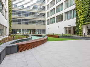 A modern building with a courtyard featuring a water feature, seating areas, and green walls. - mit Balkon am Meer by Interhome (Swinoujscie)