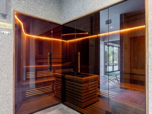 A sauna with wooden benches and glass walls, a sign indicating the sauna area, and a view of the outside through the glass. - mit Balkon am Meer by Interhome (Swinoujscie)