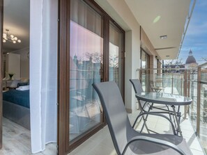 A balcony with a glass table and chairs, a sofa, and a bed in the adjacent room. - Kormoran 10 by Interhome (Swinoujscie)