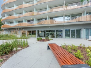 A modern multi-story building with balconies, a central courtyard, and a wooden bench. - Elegante Ferienwohnung auf der Insel Usedom by Interhome (Swinoujscie)