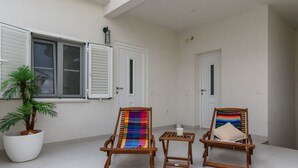 En balkon med to træstole, et lille bord og en potteplante.
