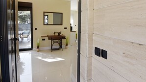 Un intérieur moderne avec une machine à coudre posée sur une table en bois, un miroir au mur et un sol carrelé.