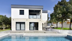 Une maison moderne à deux étages avec une piscine à l’avant.