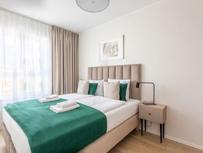 A neatly made bed with a green blanket, a headboard, and a bedside table with a lamp. - mit toller Aussicht in Swinemünde by Interhome (Swinoujscie)