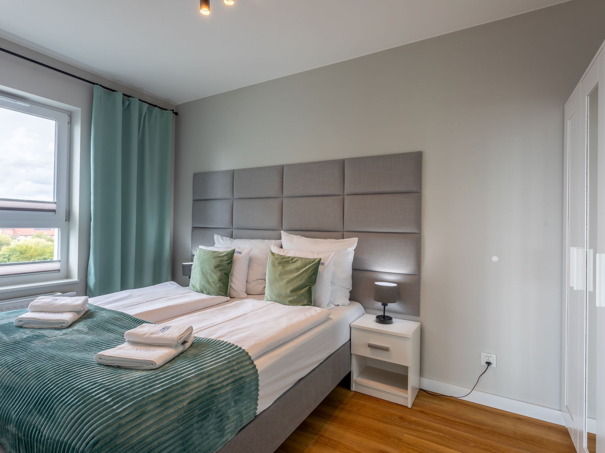 Una camera da letto moderna con un letto grande, un comodino con una lampada e una finestra con tende.