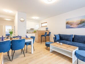 Ein modernes Wohnzimmer mit einem blauen Sofa, einem Holztisch und einem Essbereich mit blauen Stühlen und einem Holztisch.