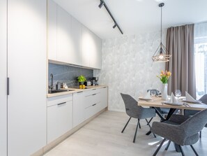 Eine moderne Küche mit weißen Schränken, einer Marmor-Spritzschutzleiste und einem Essbereich mit Tisch für zwei Personen.