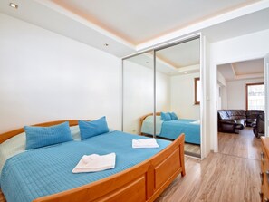 A bedroom with a large bed, a sliding glass door leading to a living area, and a wooden floor. - Silvaner am Meer by Interhome (Swinoujscie)