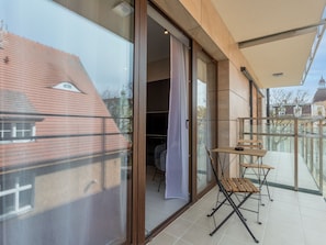 A modern balcony with a glass door leading to a room, a wooden table, and a chair. - Kormoran in modernem Appartementhaus by Interhome (Swinoujscie)