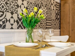 A dining table with white plates, two wine glasses, and a vase with green tulips. - Kormoran in modernem Appartementhaus by Interhome (Swinoujscie)