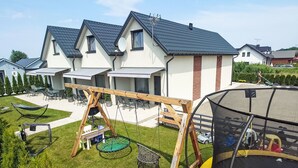 A residential property with a trampoline, a swing set, and a patio area with outdoor furniture. - Haus 1 in Sarbinowo by Interhome (Sarbinowo)