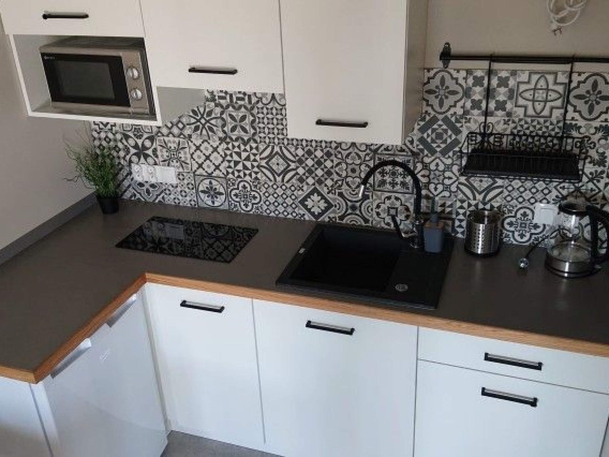 A kitchen with a microwave, sink, and patterned backsplash.
