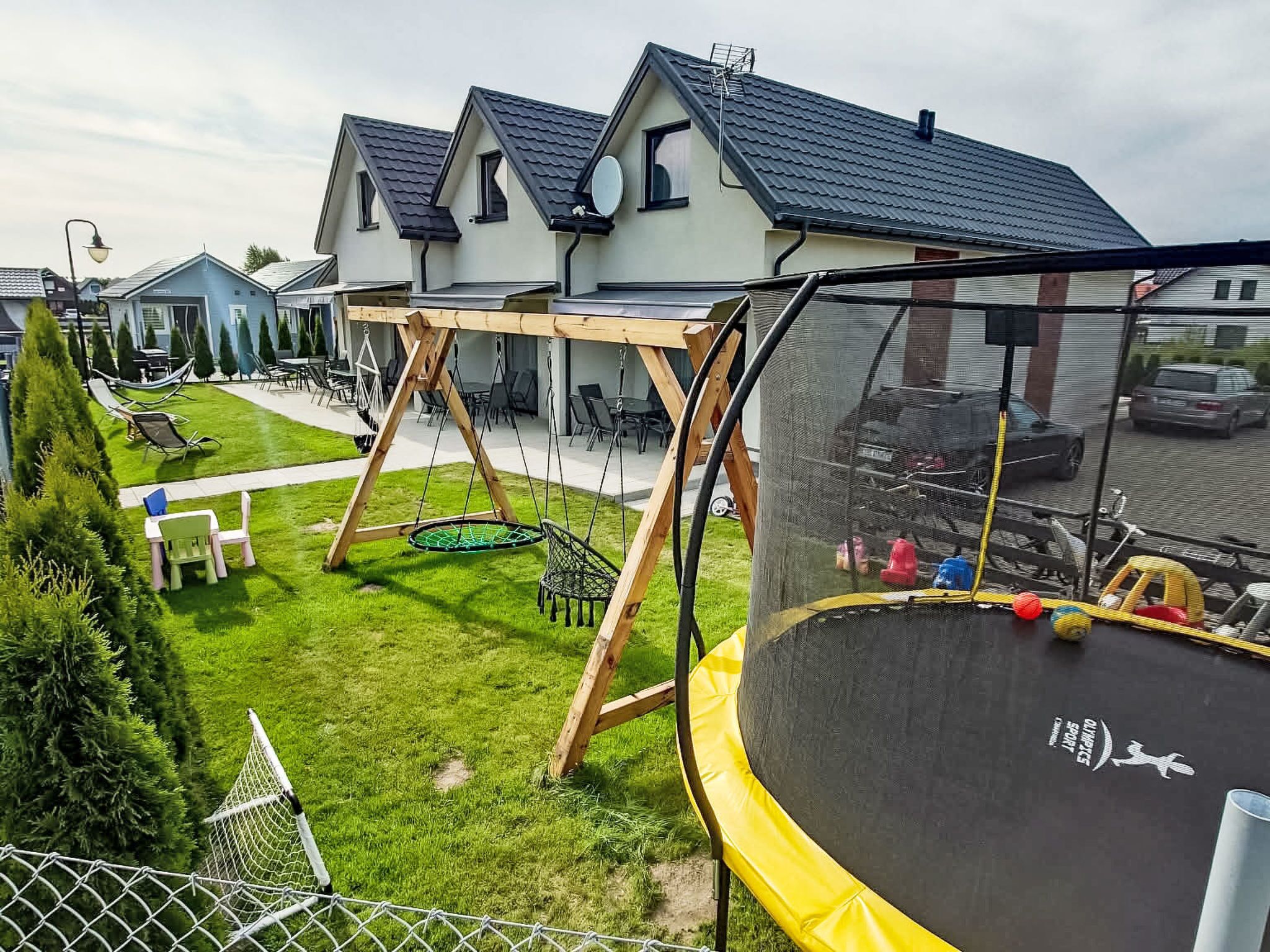 A residential area with a trampoline, swing set, and a fenced yard.