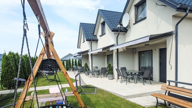 A residential property with a swing set, outdoor seating area, and a covered patio. - Haus 1 in Sarbinowo by Interhome (Sarbinowo)