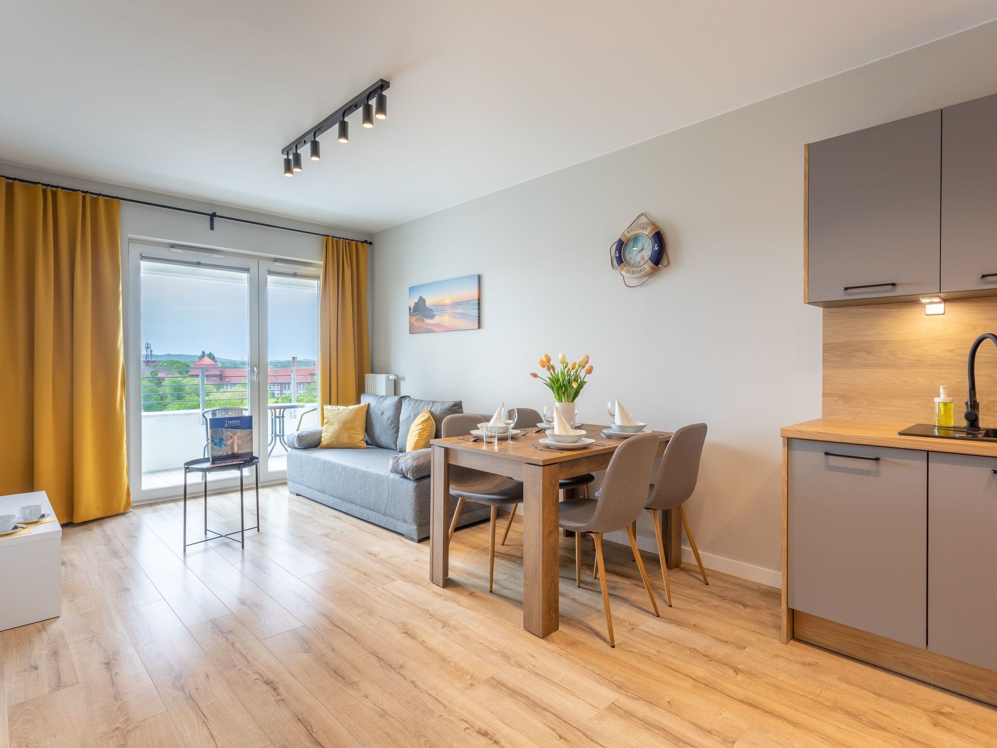 En moderne lejlighed med spiseområde, køkken og en balkon med gardiner.