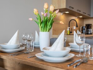 A dining table set with white plates, glasses, and silverware, accompanied by a vase of tulips. - Urlaub auf Usedom, Apartment Sun Towers A46 by Interhome (Swinoujscie)