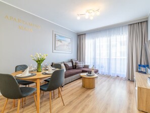 A modern living room with a dining area, featuring a wooden table, grey upholstered chairs, a sofa, and a coffee table. - Apartment Maja by Interhome (Swinoujscie)