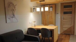 Uma sala de estar moderna com um sofá, uma mesa de jantar com cadeiras, um armário de madeira e uma luminária pendente.