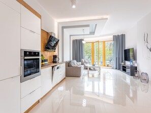 A modern kitchen with a built-in oven and a dining area with a sofa and a coffee table. - Geräumiges und luxuriöses Appartement Tower 12 by Interhome (Swinoujscie)