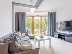 A modern living room with a sofa, a glass coffee table, and a flat-screen TV. - Geräumiges und luxuriöses Appartement Tower 12 by Interhome (Swinoujscie)