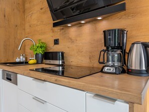 A modern kitchen with a wooden countertop, a built-in oven, a coffee maker, and a blender. - Geräumiges und luxuriöses Appartement Tower 12 by Interhome (Swinoujscie)