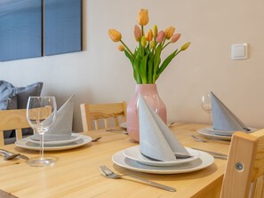 A dining table set with plates, a glass, cutlery, and a vase with tulips. - Charmante Ferienwohnung Sand auf Usedom by Interhome (Swinoujscie)