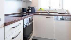 Una cocina moderna con armarios blancos, horno empotrado, cafetera y tostadora.