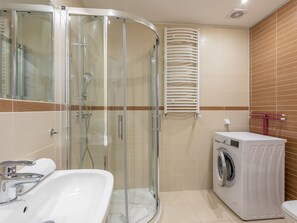 A modern bathroom with a glass shower enclosure, a white sink, and a built-in washing machine. - Pegaz 17 an der Strandpromenade by Interhome (Swinoujscie)