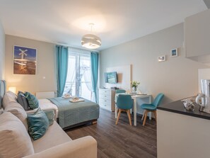A modern hotel room with a bed, a sofa, a desk with chairs, a TV, and a window with curtains. - Pegaz 17 an der Strandpromenade by Interhome (Swinoujscie)