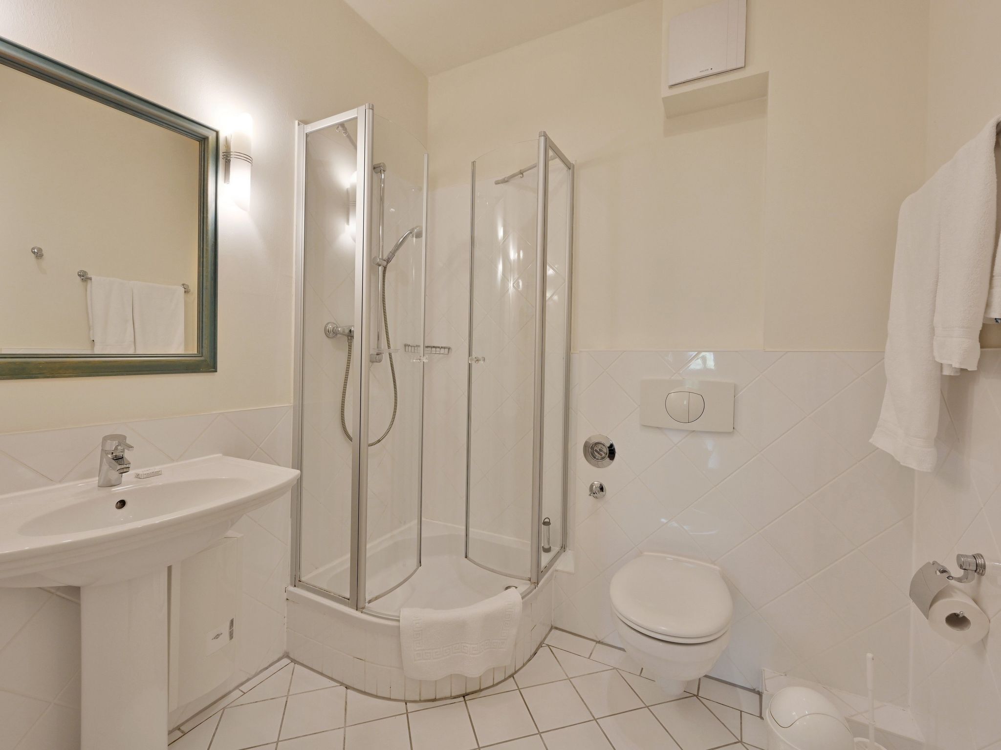 A modern bathroom with a glass-enclosed shower, a sink, and a toilet.