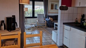 Ett kompakt kök med en matplats, en soffa och ett fönster med gardiner.