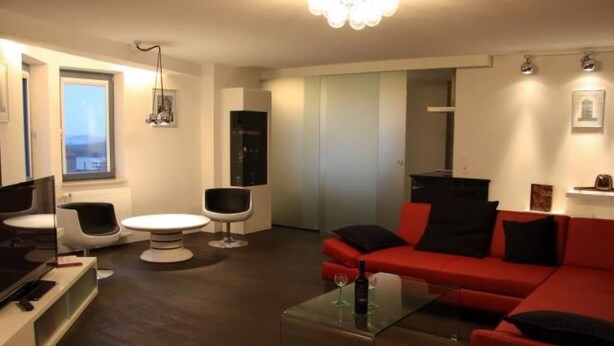 A modern living room with a red sofa, a glass coffee table, and a flat-screen TV. - Designerwohnung in denkmalgeschütztem Wasserturm by Interhome (Güstrow)