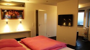A hotel room with a bed, a TV, a painting, and a bathroom visible through an open door. - Designerwohnung in denkmalgeschütztem Wasserturm by Interhome (Güstrow)