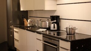 A modern kitchen with stainless steel appliances, white cabinetry, and a black marble countertop. - Designerwohnung in denkmalgeschütztem Wasserturm by Interhome (Güstrow)