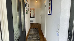A hallway with a wooden floor, a welcome mat, and framed pictures on the walls. - Vacation home  by Interhome (Burhave)